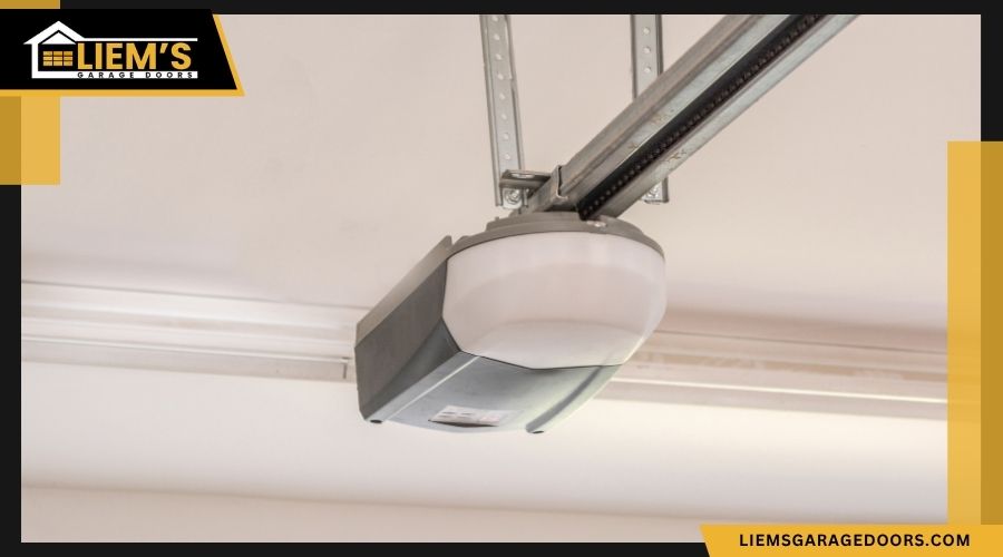 A close up view of a standard white and gray garage door opener unit installed on a garage ceiling