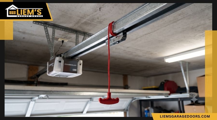 garagedoorredemergencyreleasecord The red emergency release cord hanging from an automatic garage door opener rail