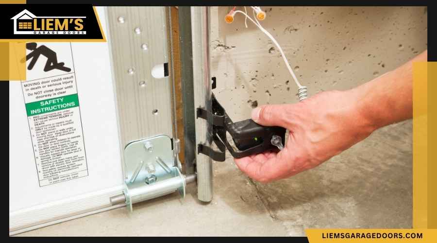 Homeowner Aligning Garage Door Safety Sensors Close up of a garage door safety sensor near the floor being inspected or aligned by hand